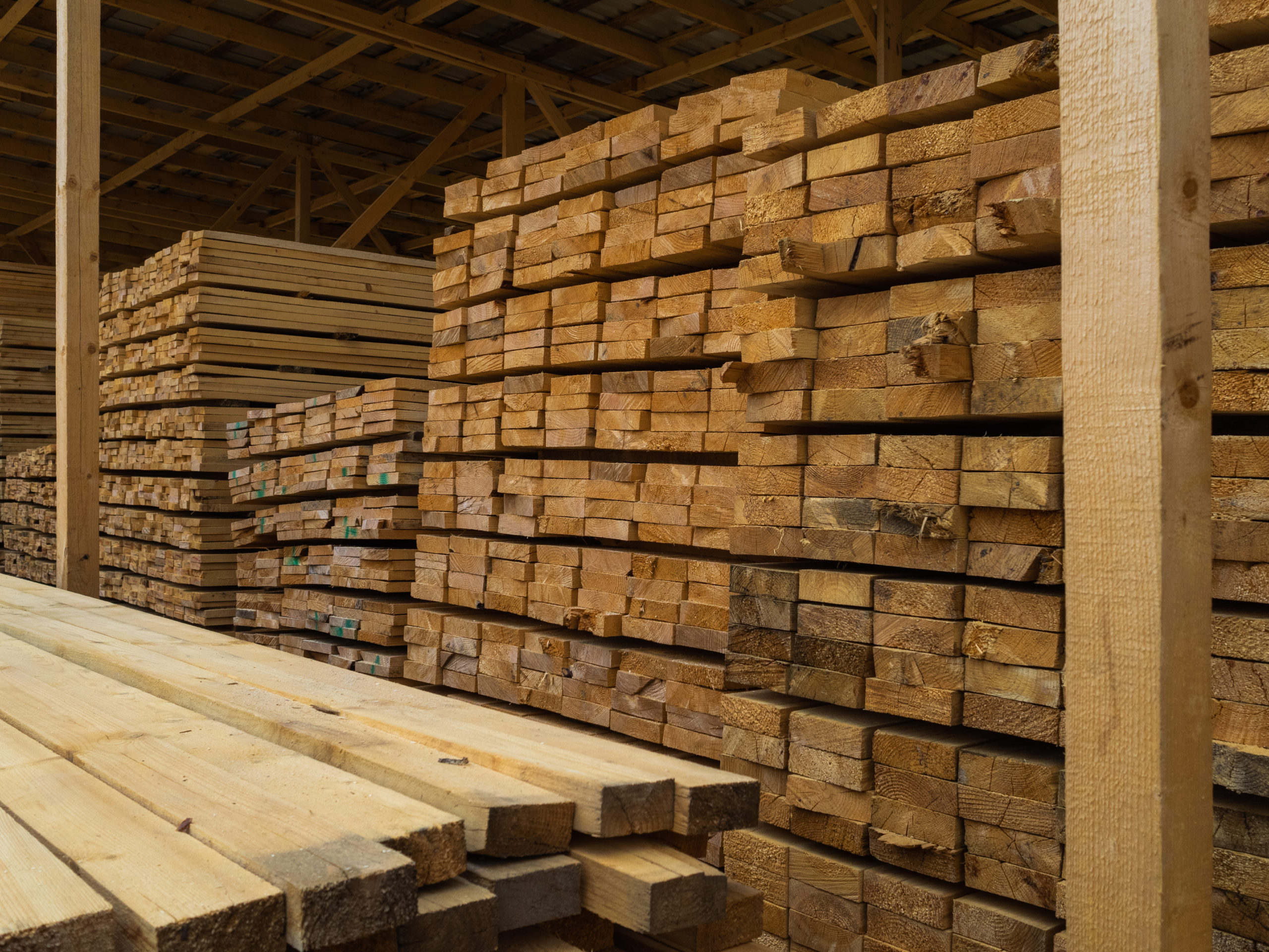 lots planks stacked top each other warehouse lumber further use construction 1 scaled