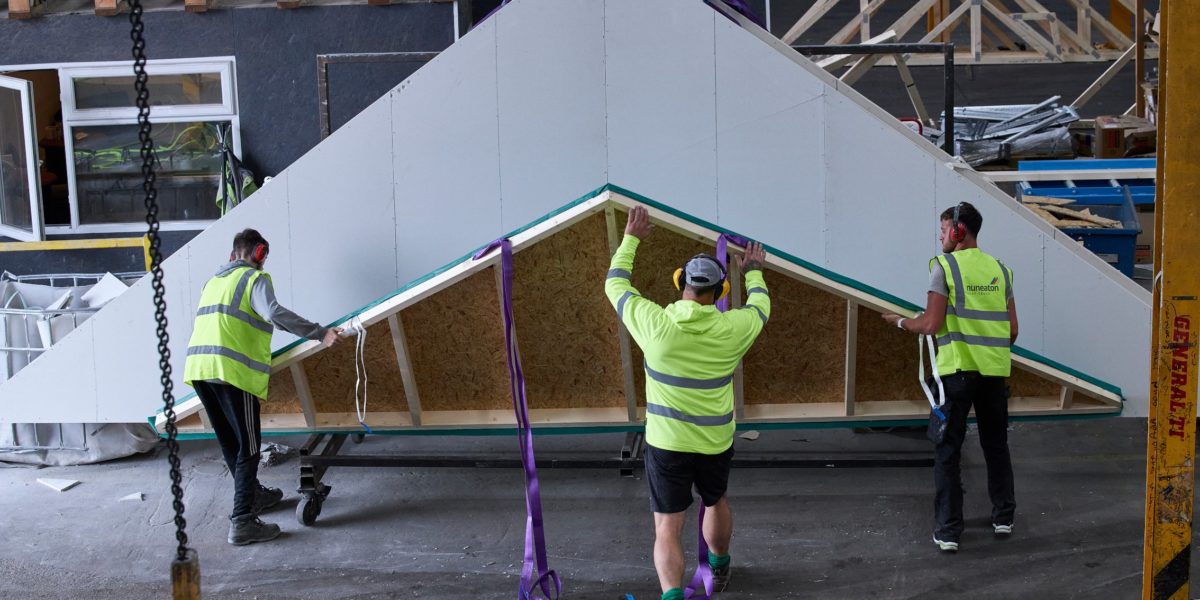 Three men moving roof trusses